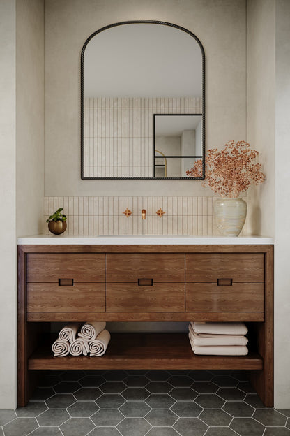 a big arch metal wall mirror above a sink with wooden storage in a bathrooom