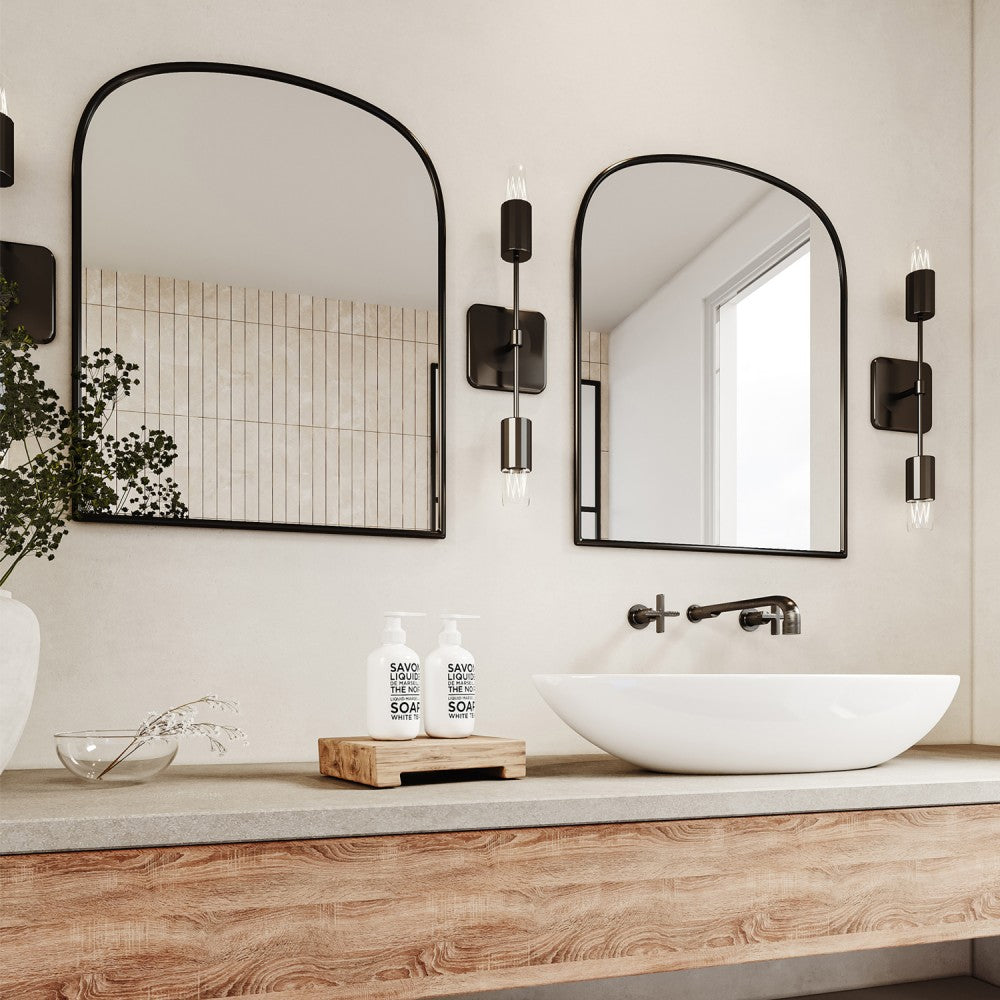 two large black arch metal wall mirror above two white sink