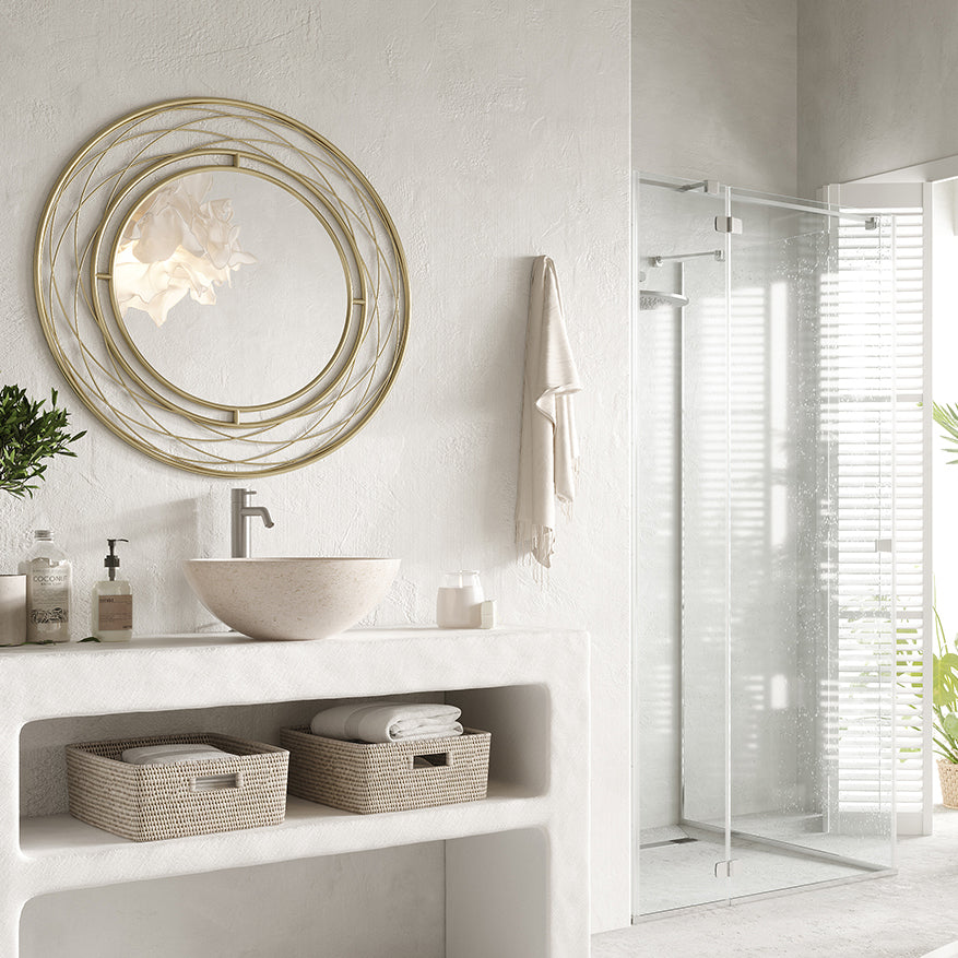 modern bathroom with a gold metal round mirror with woven frame, white concrete vanity, and vessel sink