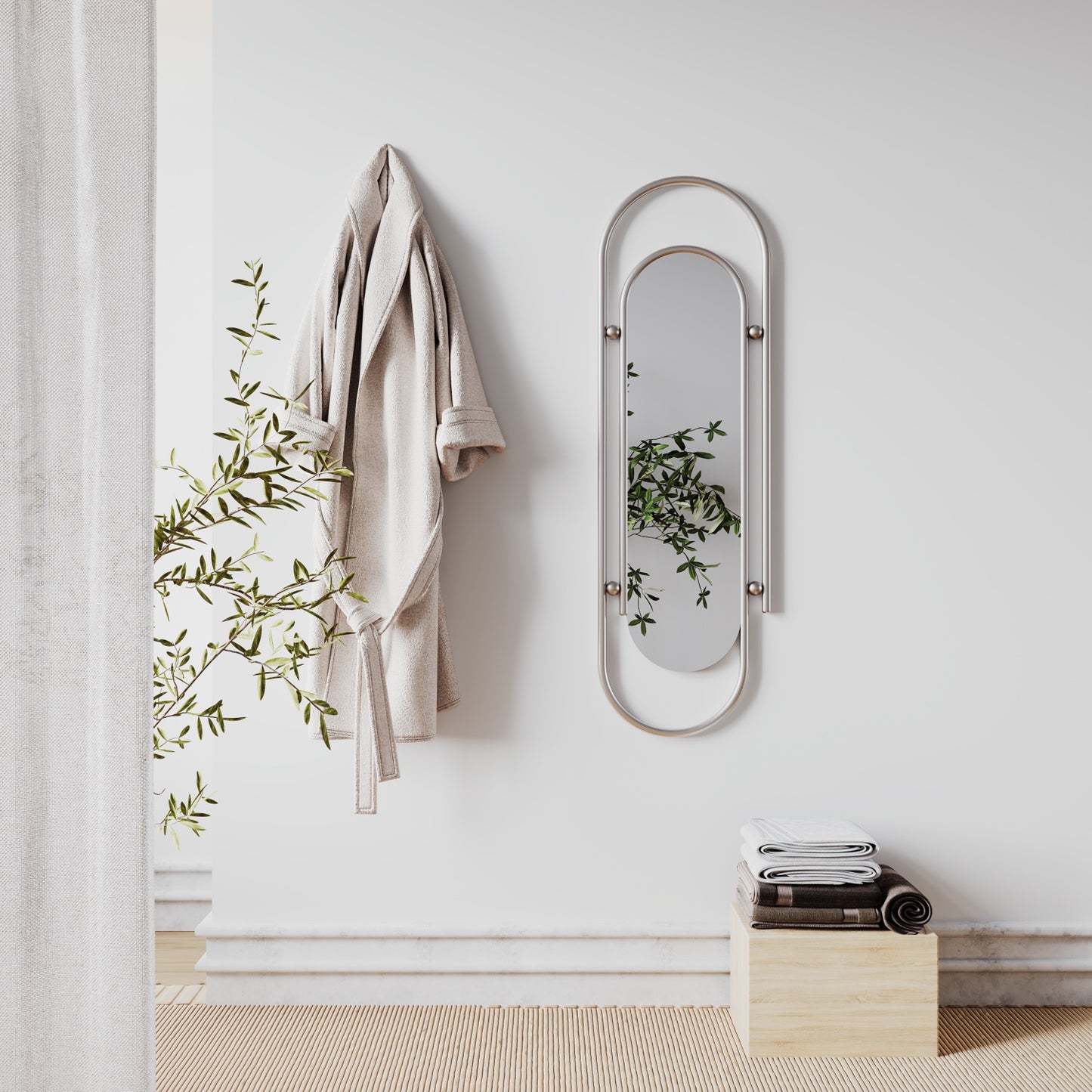 A beige bathrobe hangs next to a long pin-shaped decorative wall mirror